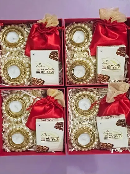 Rows of our simple yet elegant red gift boxes, each containing pearl diyas, almond brittle, and a dry fruit potli.