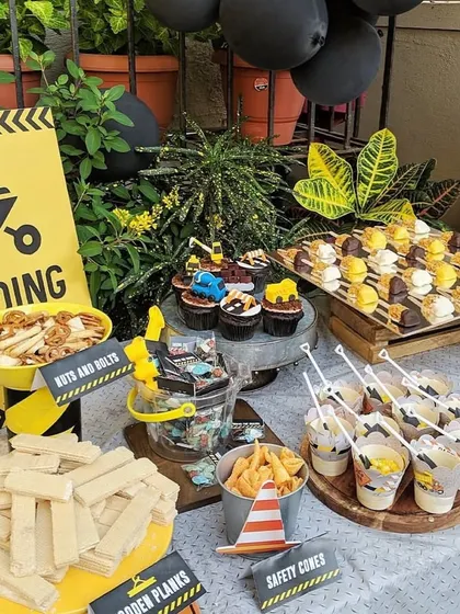 A closer look at our construction-themed party setup. The table is loaded with fun treats, including cupcakes with digger toppers and snacks served in buckets, all fitting the "loading zone" theme.
