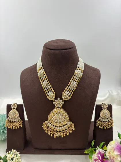 Our "Indira" premium antique gold necklace set. This long necklace features a large, intricately designed pendant with Meenakari work and comes with matching statement earrings.