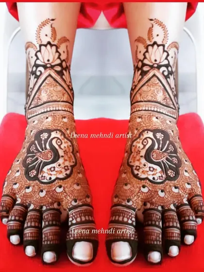 A classic bridal foot design featuring a central peacock on each foot. The feathers create a beautiful pattern over the toes, and the design extends up the ankle with lotus motifs.