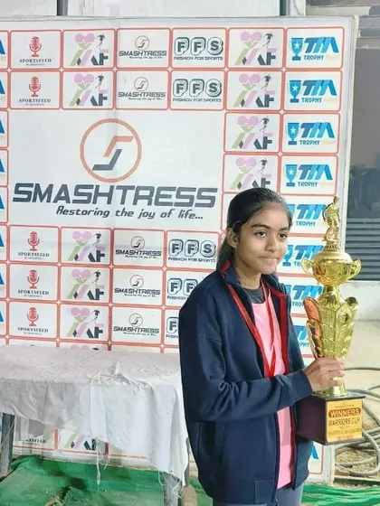 A proud player holds her winner's trophy. We celebrate the achievements of our female athletes who are faster, stronger, and better.