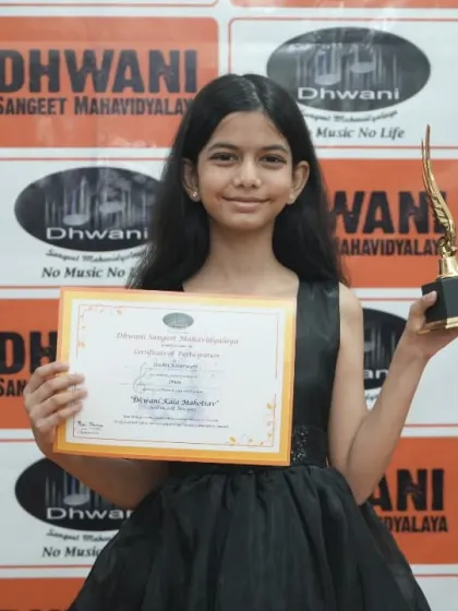 A young student in a beautiful black gown holds her award.