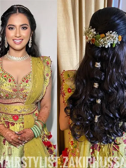 This is a unique Mehendi hairstyle with a half-updo, loose waves, and small hair rings wrapped around sections of the hair. A crown of fresh flowers completes this bohemian look.