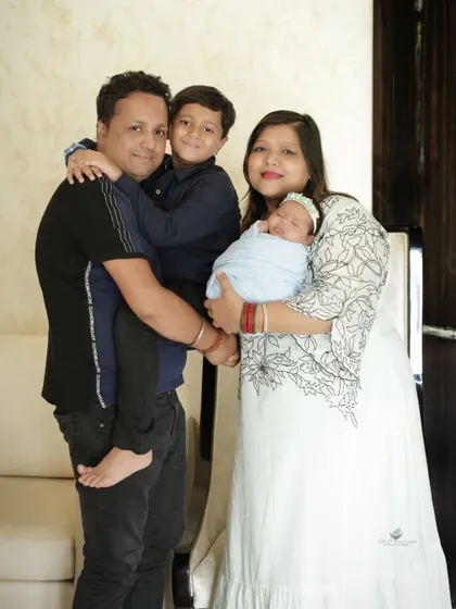 A joyful family portrait. The father holds his son while the mother holds the newborn, creating a balanced and happy image of the complete family.