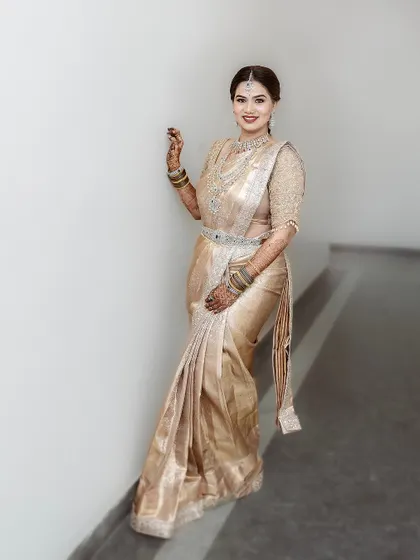 A full-length view of the bride in her beautiful golden saree and diamond jewelry. The makeup is designed to be glamorous and sophisticated for her special day.