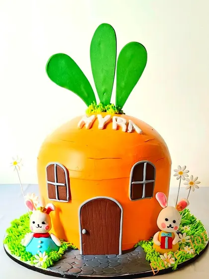 A unique carrot house cake for a bunny-themed party. This sculpted cake is shaped like a giant carrot, with two adorable bunnies outside, making it a standout centerpiece.