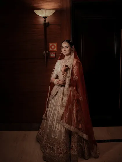 A full-length bridal portrait showcasing the bride's elegant lehenga and regal posture.