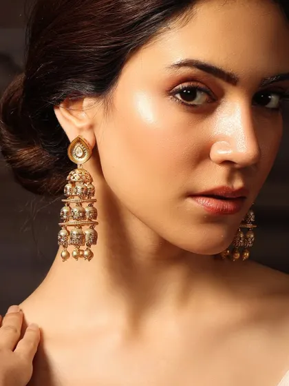 A close-up of the tiered gold jhumkas, showcasing their intricate design and delicate pearl drops.