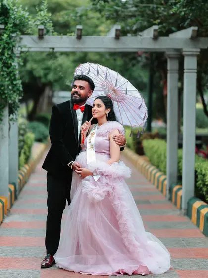This couple chose a classic look for their maternity announcement shoot. The mom-to-be is in my ruffled pink gown, complemented by her partner's black tuxedo and red bow tie.