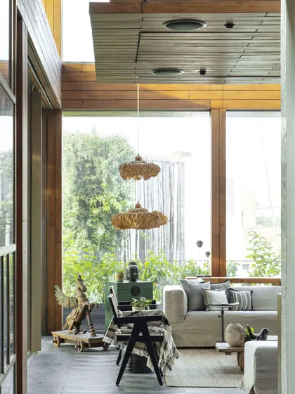 A view from the corridor into the sun-drenched conservatory. The design uses large glass panes and natural materials to blur the boundary between inside and out, creating a serene retreat within the home.