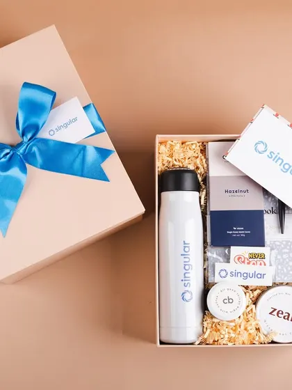 The complete unboxed view of the Singular welcome hamper. It includes a branded bottle, notebook, coffee, a scented candle, and other treats to delight a new employee.