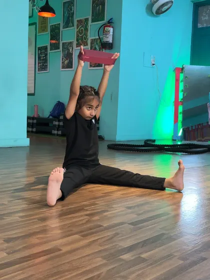 A young dancer using a yoga block to assist with her split, demonstrating her understanding of proper technique.