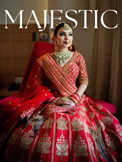 A majestic portrait of the bride sitting in her stunning red lehenga. The makeup features a bold eye and a flawless base, creating a look that is both powerful and elegant.