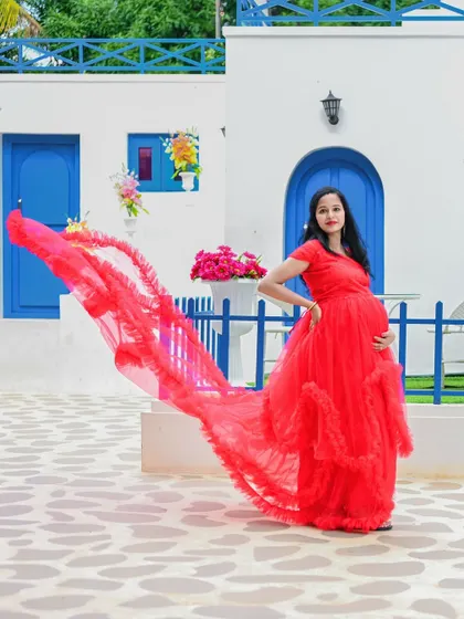 The flowing red gown looks incredible against the Santorini-style white and blue architecture. This is a perfect example of a destination-feel shoot.