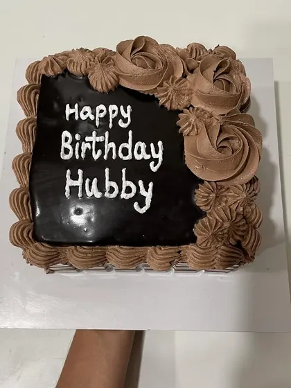 A square chocolate cake with a rich ganache topping and piped cream roses, perfect for a husband's birthday.