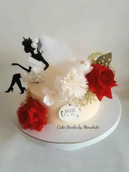 A stunning cake for a bride-to-be, made with zero fondant. The design features a classic silhouette topper and is adorned with beautiful red and white flowers.