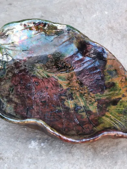 The final result of a Raku-fired leaf platter. The glazes have produced a stunning mix of metallic greens, blues, and coppers. The result is always a beautiful surprise.