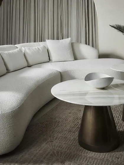 The Poet Sofa in a pristine white bouclé fabric, paired with our Cone Round Coffee Tables. The combination of the sofa's soft, curved form and the tables' sculptural marble tops creates a look of pure, understated luxury and modern elegance.