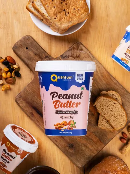 A top-down flat lay of Quantum Nutrition's peanut butter, surrounded by its ingredients like nuts and bread. This styling connects the product to a healthy, wholesome lifestyle.