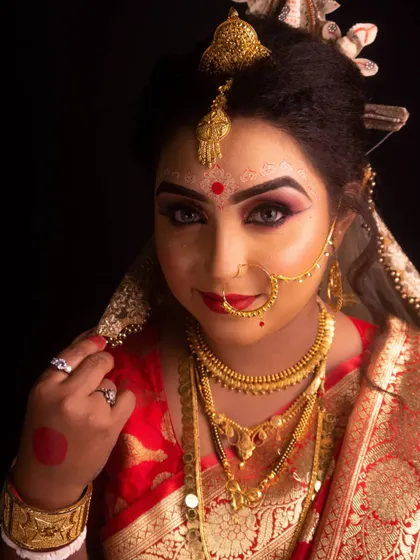A close-up portrait of a Bengali bride, showcasing her traditional gold jewelry and the radiant red bindi. Our team is skilled in capturing the cultural richness of different wedding ceremonies.