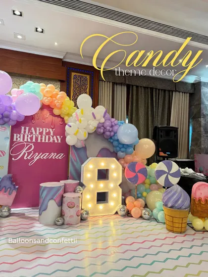 A closer look at the Candyland decor, with giant ice cream cone props and a pastel rainbow balloon garland.