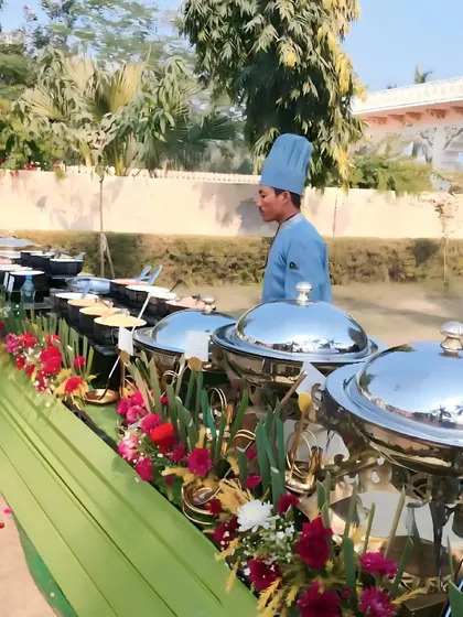 A chef at our outdoor live counter, ready to serve guests. The setup includes a variety of prepped ingredients and sauces, allowing for customized dishes made to order.