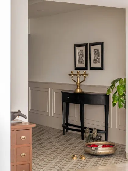 A quiet corner in the foyer, featuring a traditional console table and brass accessories. The wainscoting and patterned floor tiles add a layer of heritage and old-world charm to the entryway.
