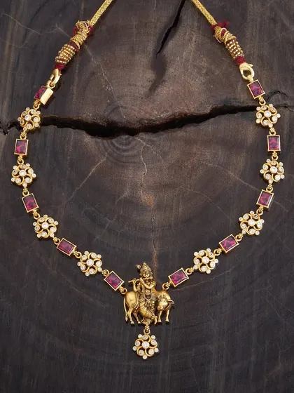 A simple yet divine necklace featuring a pendant of Lord Krishna playing the flute, accompanied by a cow. The chain is adorned with alternating floral motifs and square-cut red stones.