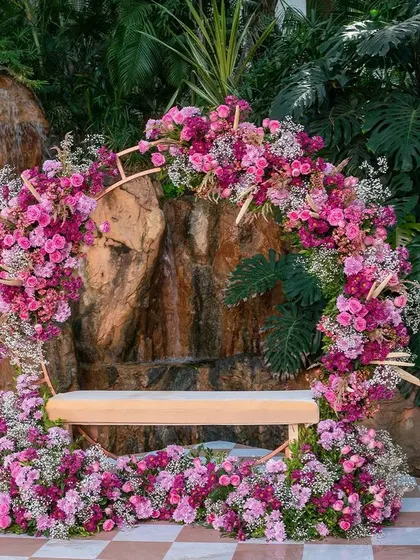 A circular floral seating arrangement, perfect for the bride during her Mehendi ceremony. This beautiful wreath of pink flowers creates a stunning photo backdrop against the natural rock waterfall.