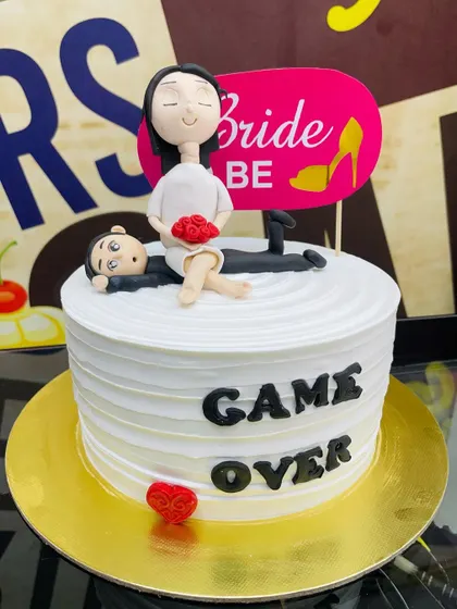 A humorous 1.5kg "Game Over" cake for a bride-to-be, with a fondant couple topper.