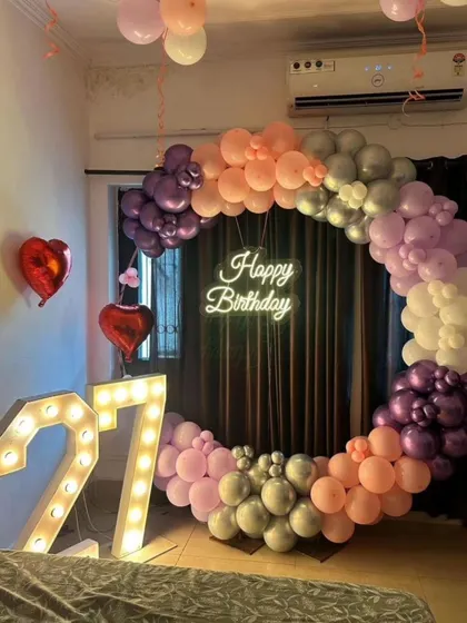 A simple yet beautiful bedroom decoration for a 27th birthday. The circular balloon arch and marquee numbers create a personal and intimate celebration space.