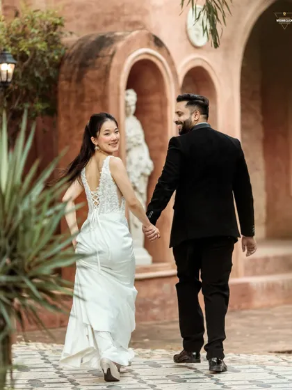 A classic "follow me" shot with a joyful, over-the-shoulder glance. This pose is perfect for capturing movement and happiness, showing off the beautiful back details of her dress against the elegant European-style architecture.