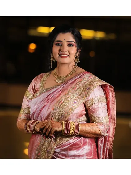 A beautiful solo portrait of the bride, showcasing her elegant pink saree and traditional jewelry. Her radiant smile lights up the frame.