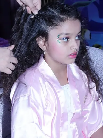 A girl gets her hair braided and styled, complete with glitter makeup, as part of her mermaid spa day experience.