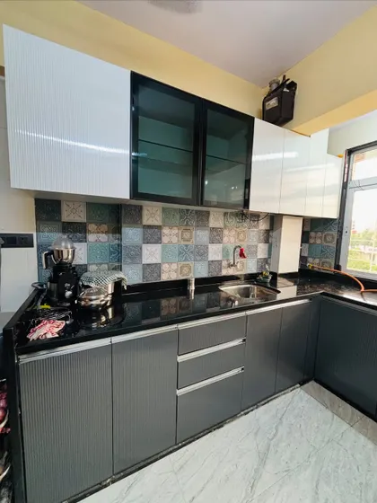 This kitchen combines modern grey fluted cabinets with white overhead units. The patterned tile backsplash adds a playful, decorative touch.