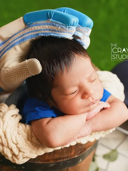 A creative shot with a large batting glove gently resting on the sleeping baby's head, symbolizing a parent's love for both their child and the sport.