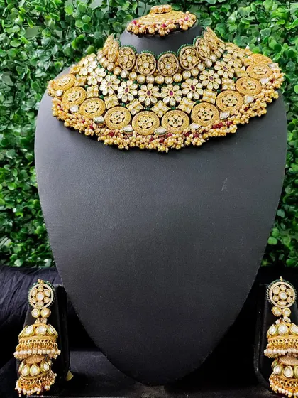 A beautiful rental set featuring a wide choker with intricate floral and coin motifs. The matching oversized jhumkas make this a statement piece for any bride.