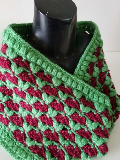 The red and green Cardamom Blossoms cowl displayed on a mannequin. This shows how it sits comfortably around the neck, providing plenty of warmth.