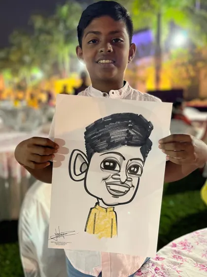 A young guest at the Ambegaon wedding, proudly holding his caricature.