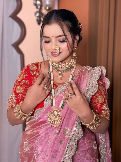 The bride looking down, showcasing her beautiful eye makeup and the heavy traditional necklace.