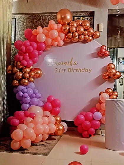 A colorful and chic decoration for a 31st birthday. This setup uses a custom backdrop panel and a balloon arch with a beautiful blend of pink, purple, and rose gold chrome balloons.