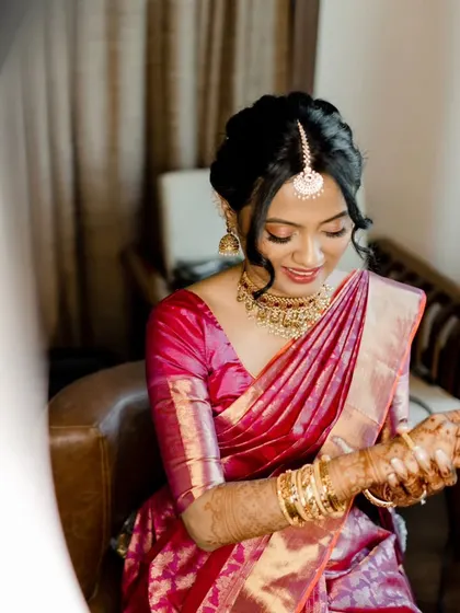 A closer look at this South Indian bride's look. Notice the soft updo with delicate tendrils framing her face and the beautiful gold jewelry that completes her ensemble.