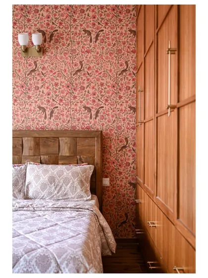 A parent's bedroom featuring a beautiful floral Sabyasachi wallpaper, balanced by a tall, custom wooden wardrobe with sleek brass handles.