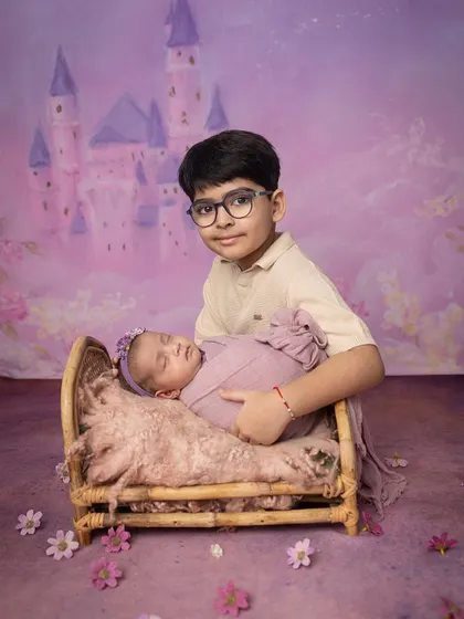 A proud big brother stands guard over his sleeping sister in her fairytale cot. This shot combines the magic of a theme with the reality of a new sibling bond.