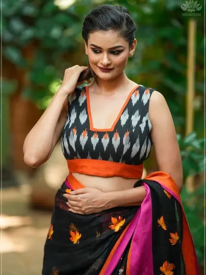 A sleeveless Ikat blouse in a black, white, and orange pattern. The V-neck and bold print make it a modern and eye-catching choice.
