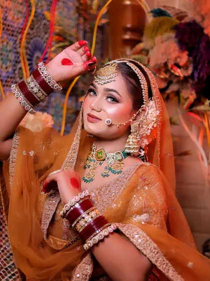 A vibrant portrait showcasing the bride's traditional look. The alta on her hands and her pose pay homage to classic Indian bridal customs, beautifully complementing her mustard-gold outfit.