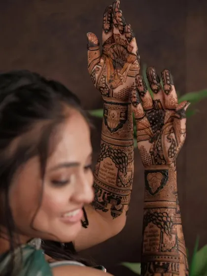A bride admiring her full-arm mehandi. The design features traditional wedding scenes and intricate patterns, creating a stunning piece of art.