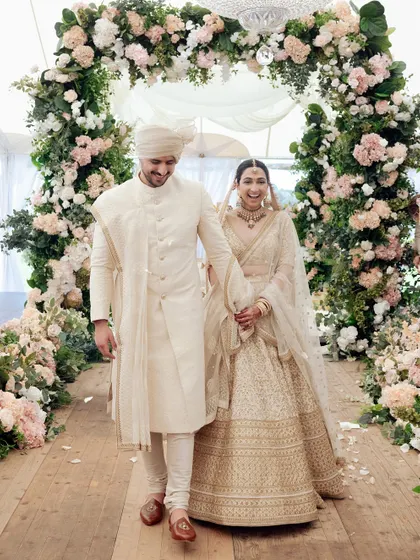 The couple's triumphant walk down the aisle after their ceremony in Brisbane. The floral arch and joyful expressions make this a perfect celebratory photograph.