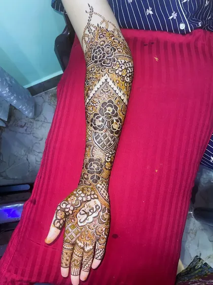 A single arm view of the bridal henna, with the groom's name "Moin" clearly visible on the palm.