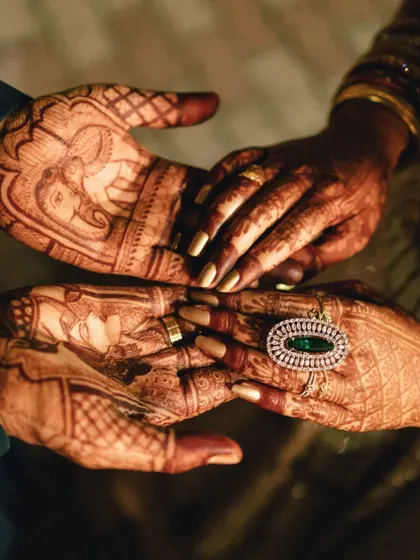 A beautiful shot of the couple's hands, showcasing the intricate mehendi designs that tell their story. The bride's elegant ring adds a touch of modern glamour to the traditional art.